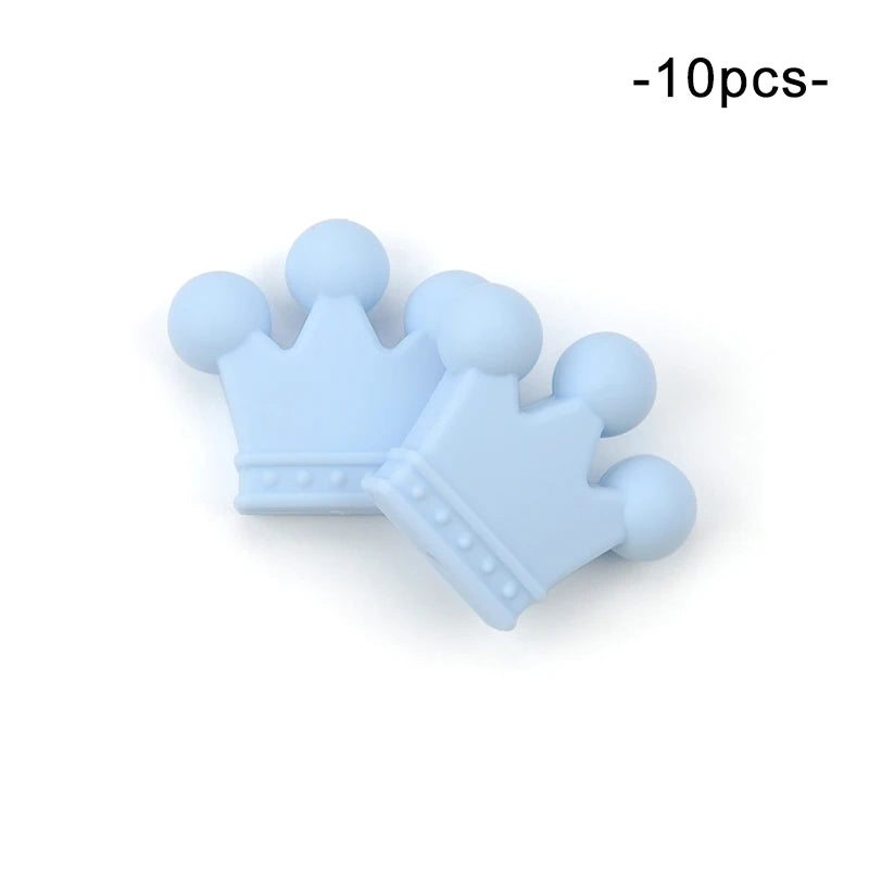 Two light blue crown-shaped silicone beads with dotted details, arranged slightly overlapping. The image mentions a set of 10 pieces.