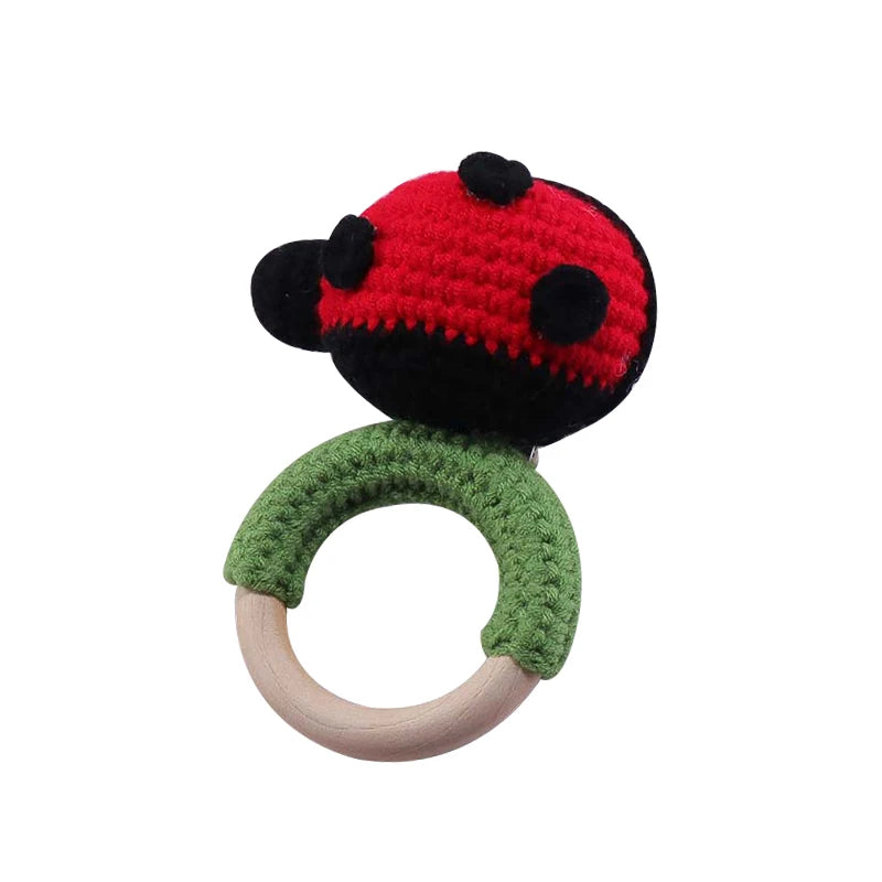 Crocheted ladybug baby rattle with a red and black ladybug on a green yarn-covered wooden ring.
