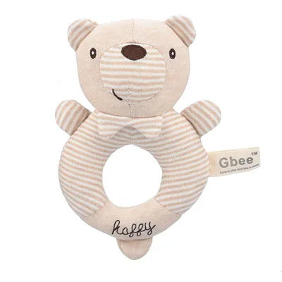Plush teddy bear rattle with a striped beige and white pattern, circular body, and embroidered "happy" text. It has a small tag on the side with "Gbee" on it.