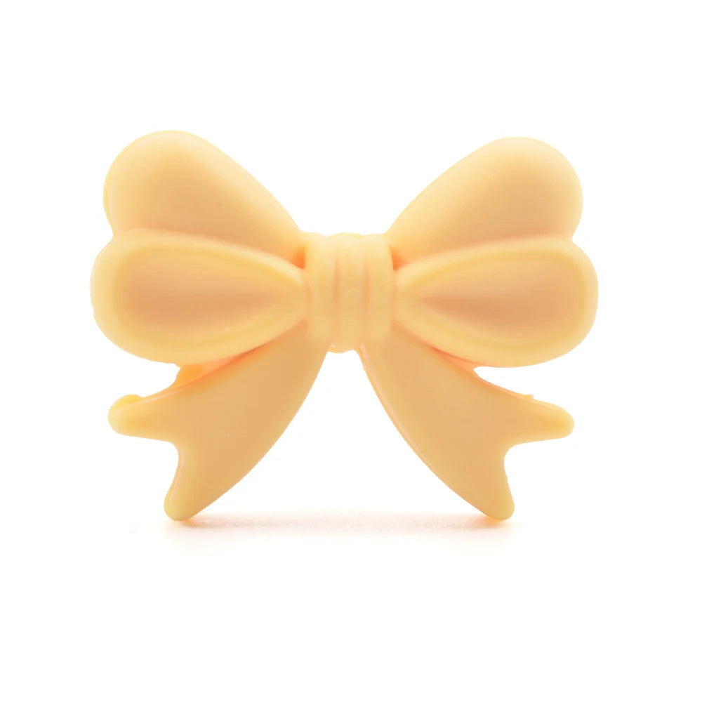 A soft yellow rubber bow-shaped dog toy, with two loops and tails, isolated on a white background.