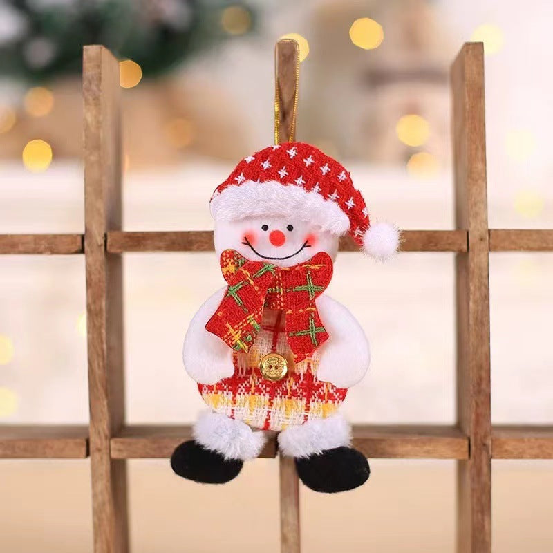 Festive snowman ornament with a red Santa hat, plaid scarf, and checkered body, hanging on a wooden rack. Blurred lights in the background create a cozy atmosphere.
