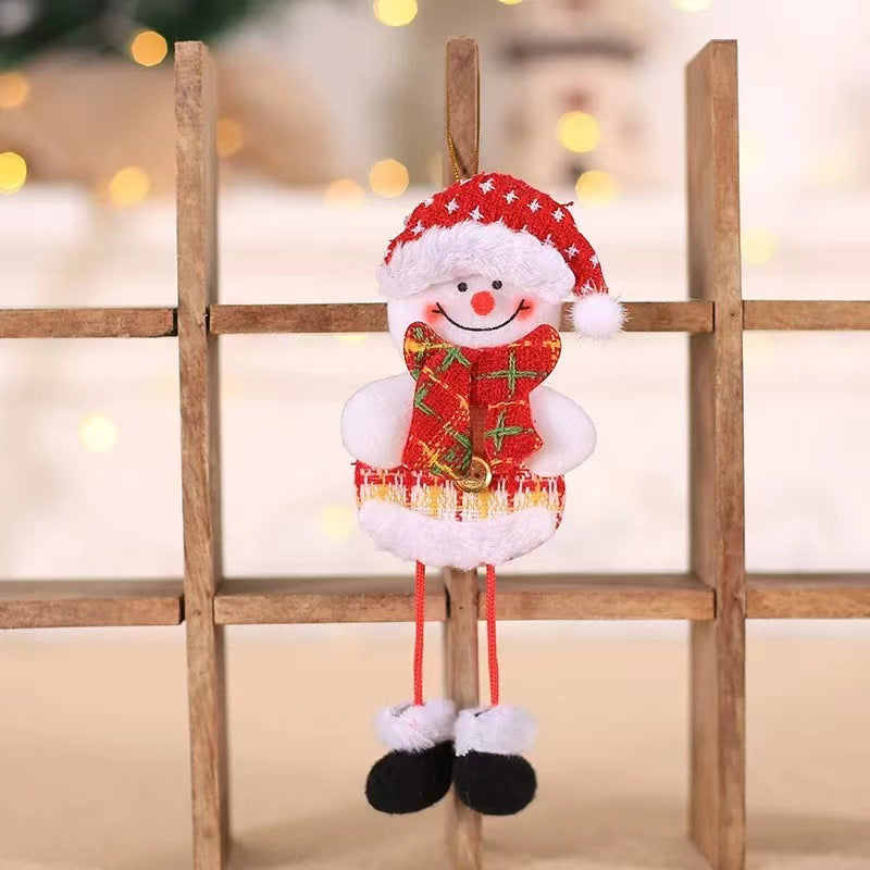 Cute snowman ornament in a red Santa hat and scarf, hanging on a wooden grid. Soft background lights create a festive atmosphere.