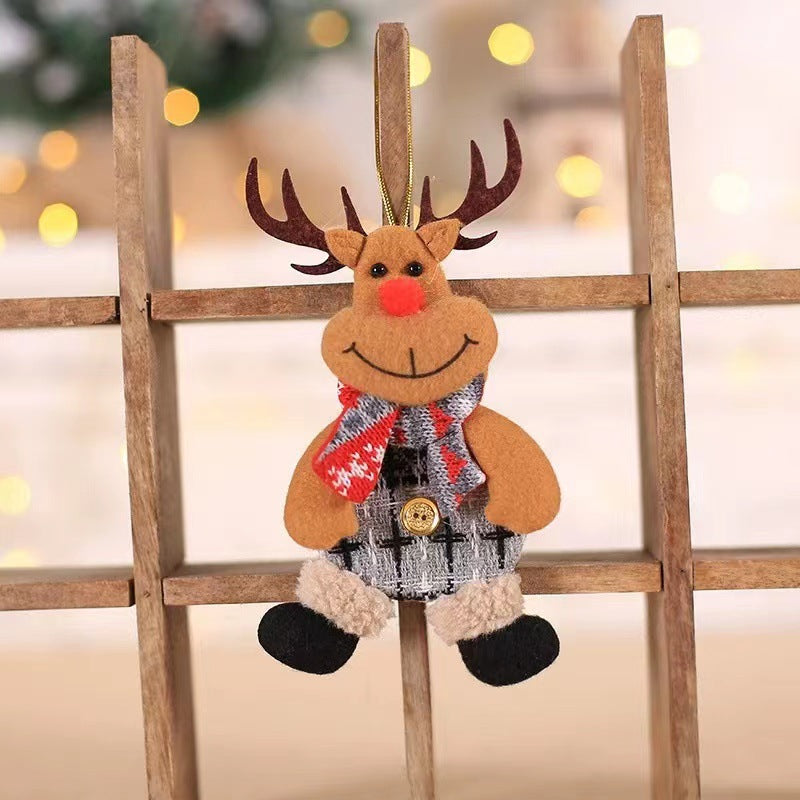 A cute felt reindeer ornament with antlers, a red nose, plaid scarf, and buttoned outfit hangs on a wooden lattice. Soft focus lights create a warm, festive background.