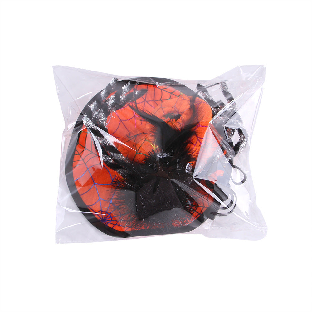 Plastic-wrapped Halloween decoration featuring a black spider on an orange, web-patterned circular base with accent colors, secured in transparent packaging.