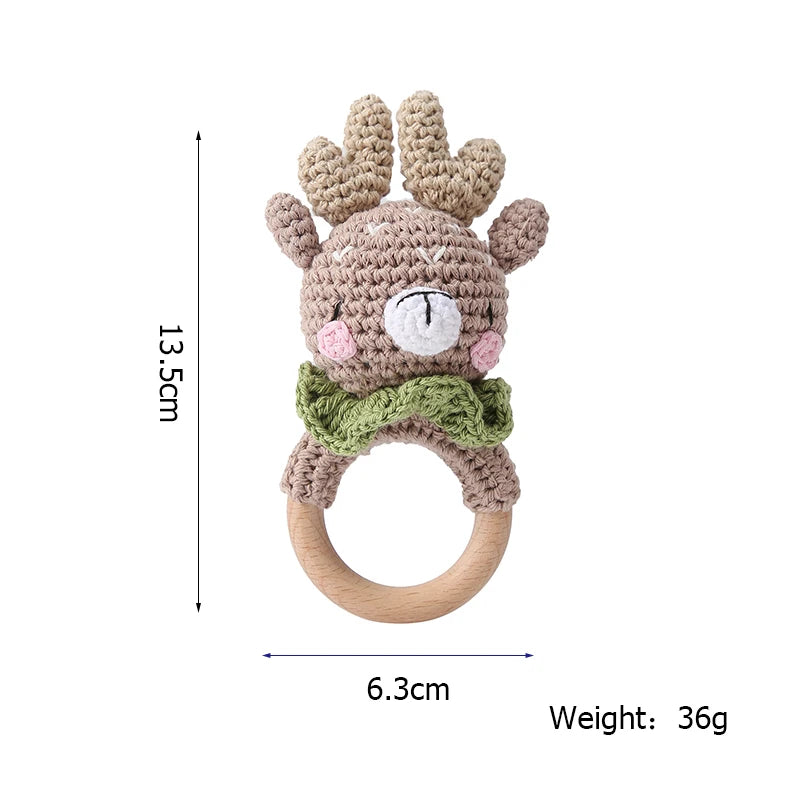 Crocheted deer-shaped baby rattle with antlers and green bow tie. Features a wooden ring, measuring 13.5 cm in height and 6.3 cm in width. Total weight is 36 grams.