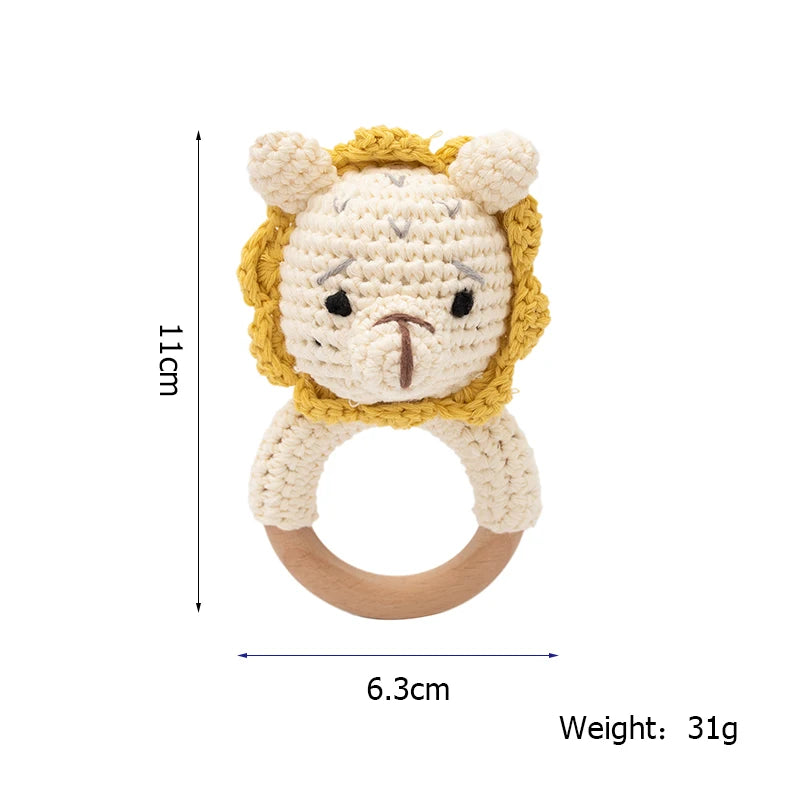 Crocheted lion baby rattle with a wooden ring. Dimensions: 11cm tall, 6.3cm wide, weighing 31g. Cream and yellow colors, featuring a cute lion face.