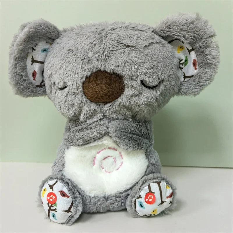 Cute grey plush koala with closed eyes, a brown nose, and a white belly featuring a swirl design. Patterned ears and feet with colorful birds and music notes.