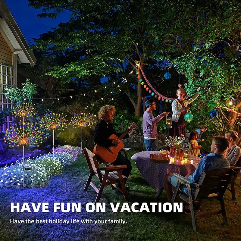 A family enjoys a cozy evening in a garden with colorful string lights. One person plays guitar while others sit around a table. Festive decorations and glowing lanterns create a joyful atmosphere.