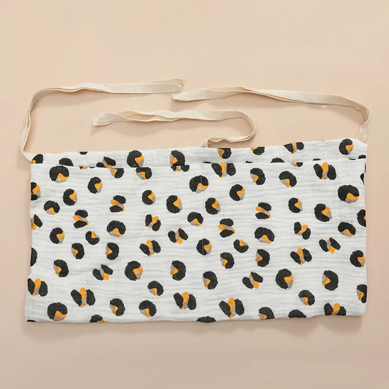 White fabric belt with black and orange leopard print pattern, featuring beige ties for fastening, set on a neutral background.