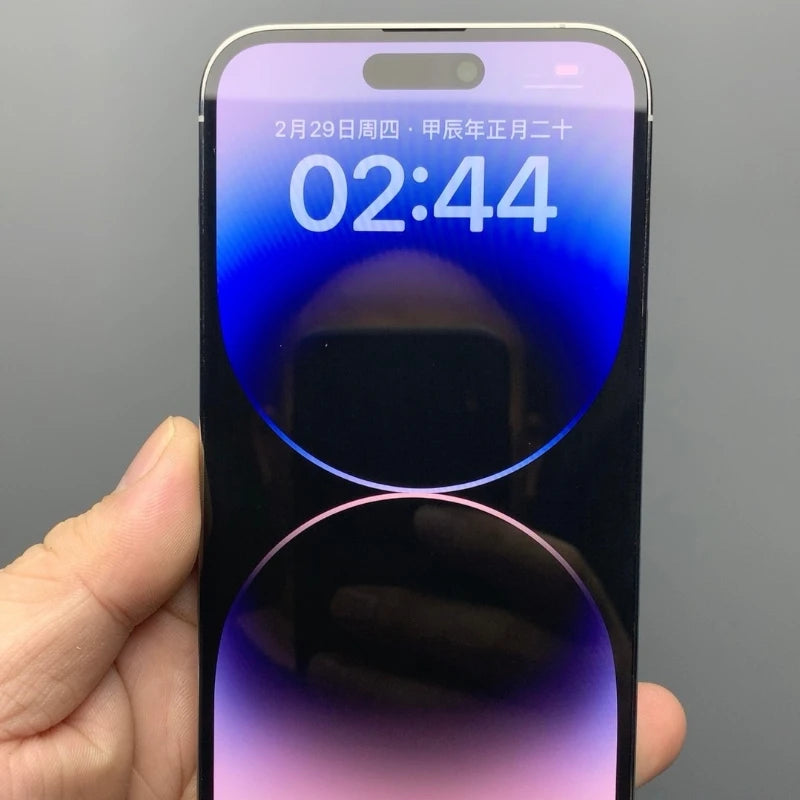 A hand holds a smartphone displaying the time 02:44 and date February 29. The screen shows a gradient of blue and purple circles with a pill-shaped sensor area at the top.