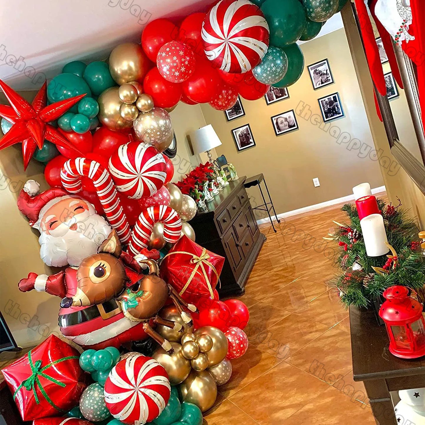 Festive Christmas decor with balloons featuring Santa, reindeer, candy canes, and gifts. Red, green, and gold hues adorn a living room with candles and framed photos on the wall.