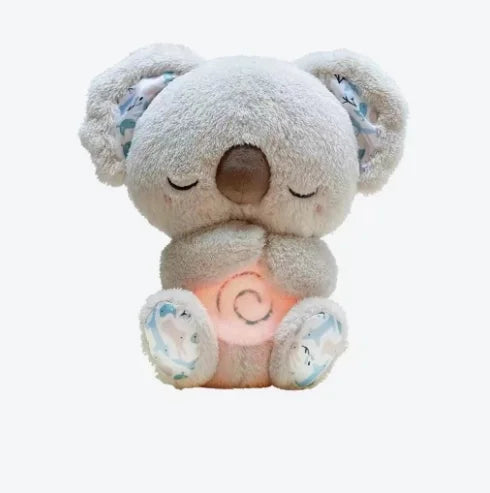 A plush koala toy, light gray with floral-patterned ears and feet, sits with closed eyes. Its stomach glows softly in a pink hue against a plain white background.