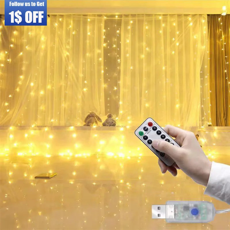 Hand holding a remote control, pointing at warm white string lights hanging on a curtain. Two plush toys sit among the lights, and a USB connector is visible in the foreground.