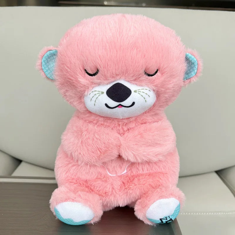 A cute pink plush bear with turquoise inner ears sits with its eyes closed, smiling serenely. It has a stitched nose and mouth, and white details on its feet.