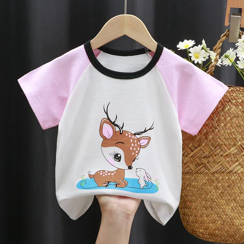 Children's t-shirt with pink sleeves, featuring a cute illustration of a deer and a rabbit sitting by a pond. The shirt hangs on a wooden hanger against a dark background.