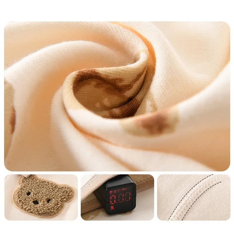 Close-up of a soft, beige fabric with brown patterns. Includes a teddy bear patch detail, a digital display with red numbers, and neat stitching along the seams.