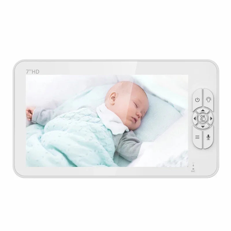 A 7-inch HD screen displays a sleeping baby dressed in pastel green, lying on a soft pillow. Remote control buttons for camera and audio functions are on the side.