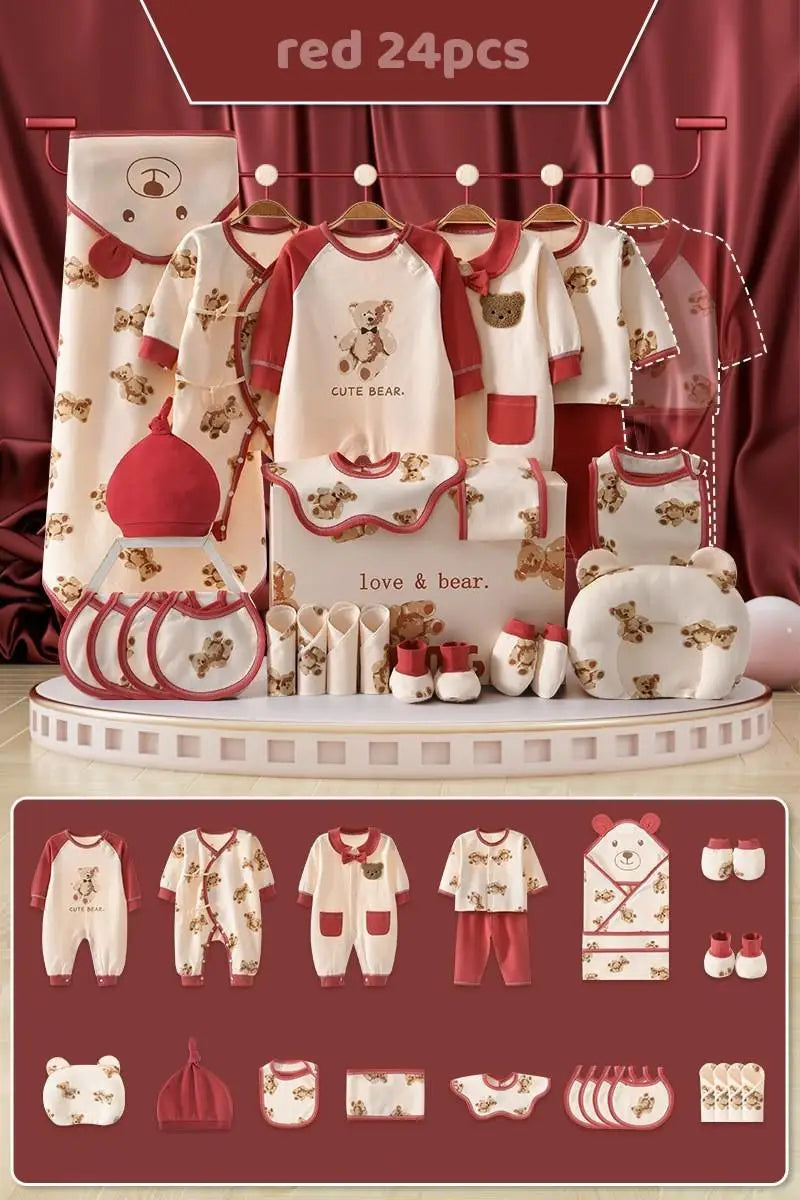 A 24-piece red and beige baby clothing set with bear designs, including rompers, bibs, hats, and socks, displayed on a rack against a red curtain backdrop.