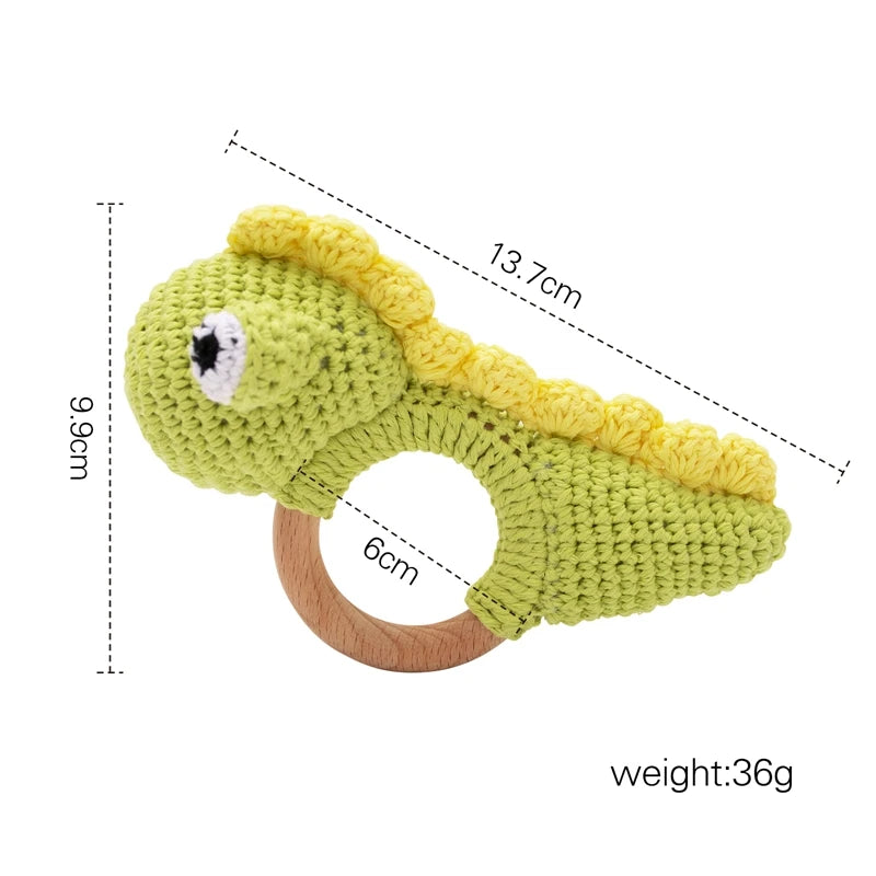 Green crochet dinosaur baby teething ring with wooden handle. Dimensions: 13.7cm long, 9.9cm tall, handle diameter 6cm. Features yellow spikes and a cute eye, weighing 36g.
