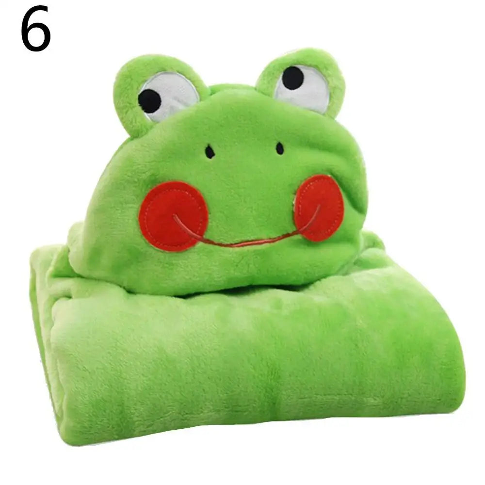 A green plush blanket folded with a frog face hood featuring big eyes, red cheeks, and a smiling mouth. A black number six is in the top left corner.