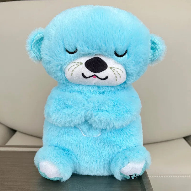 A fluffy blue teddy bear with closed eyes, sitting upright. It has a soft texture, a cute, smiling face, and crossed arms. The background is a light-colored sofa.