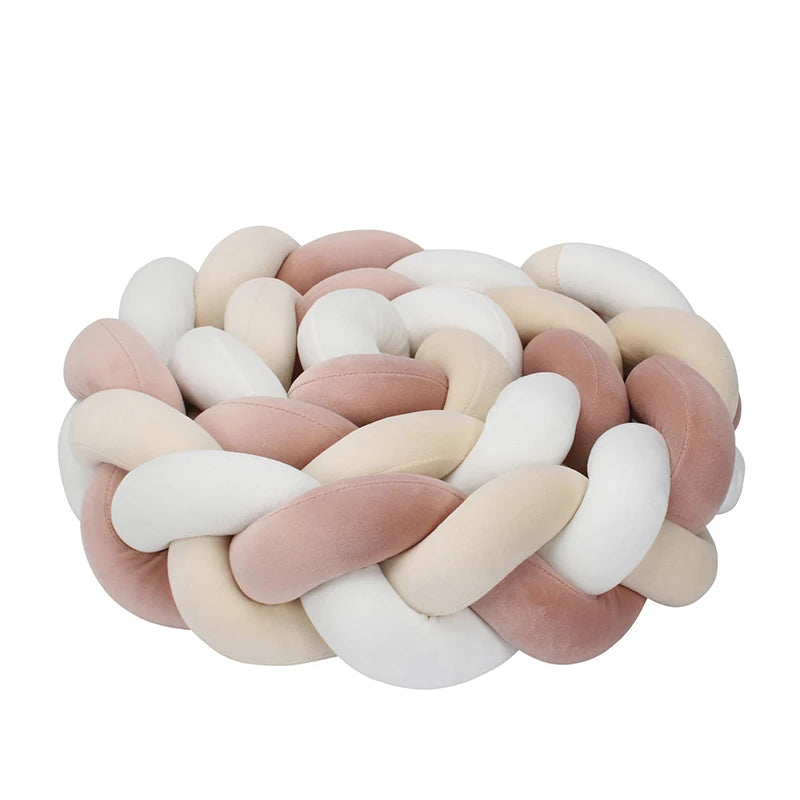 Soft, woven cushion with a braided design in pastel shades of pink, beige, and white, creating a cozy, decorative look suitable for home decor or seating.