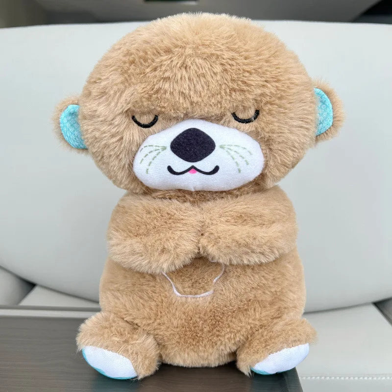Cute brown plush bear with eyes closed, light blue inner ears, and a small smile. The bear is seated on a gray surface in a relaxed pose.