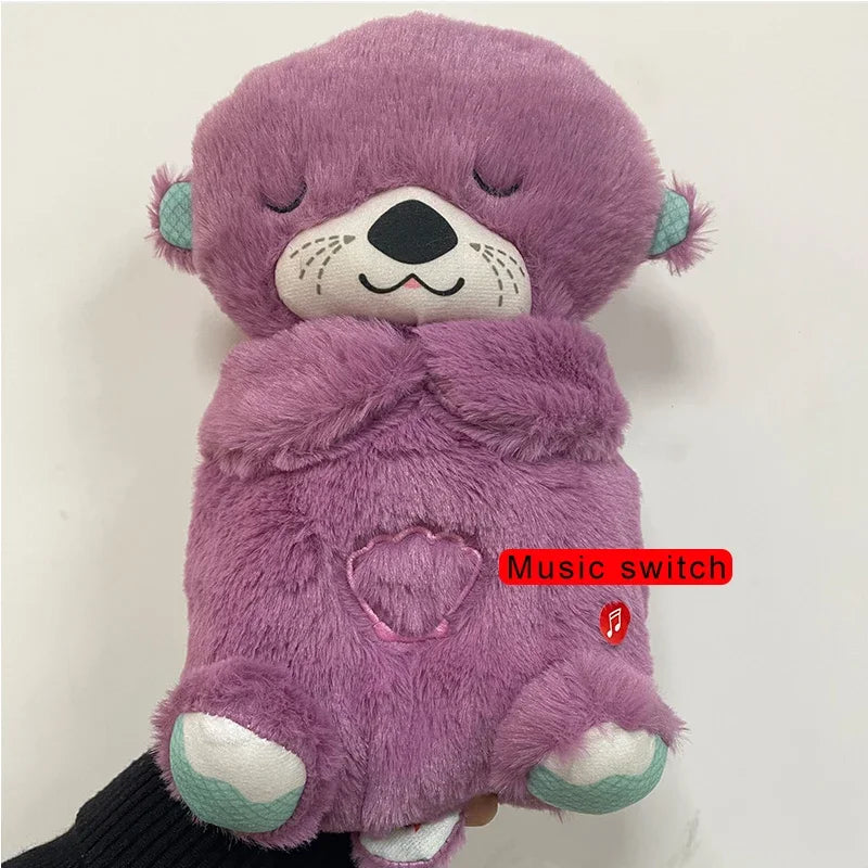 Purple plush otter toy with closed eyes, black nose, teal ears, and white paws. It has a heart-shaped music switch on its belly, highlighted in red text.
