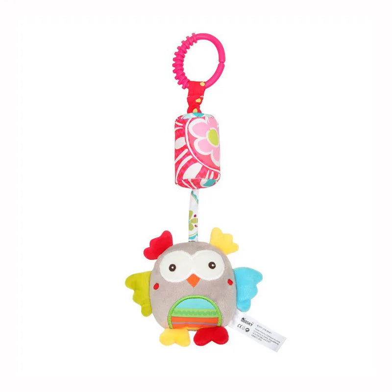 Colorful plush owl toy with red, yellow, and blue wings, hanging from a pink floral-patterned strap with a textured ring for attachment.