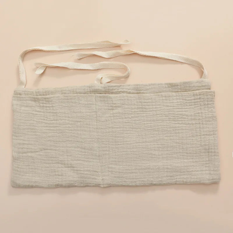 Light gray, textured fabric wrap with four white tie strings on a beige background. The wrap appears rectangular and made of a soft material.