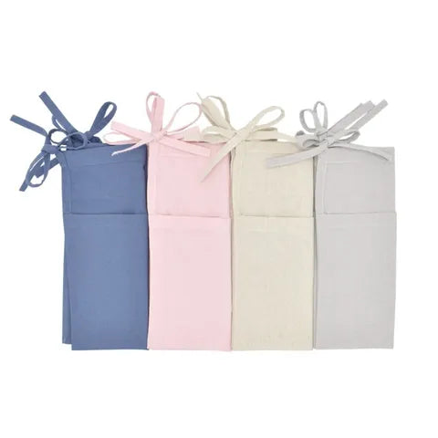 Four neatly folded aprons in blue, pink, beige, and gray colors, each tied with matching bows, are arranged side by side against a white background.