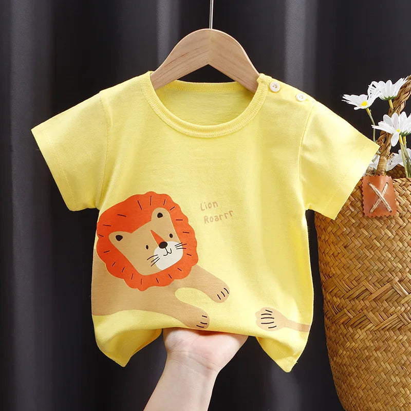 Yellow toddler t-shirt with a cute lion illustration and "Lion Roarrr" text. Displayed on a wooden hanger, a hand holds it near a woven basket with white flowers.