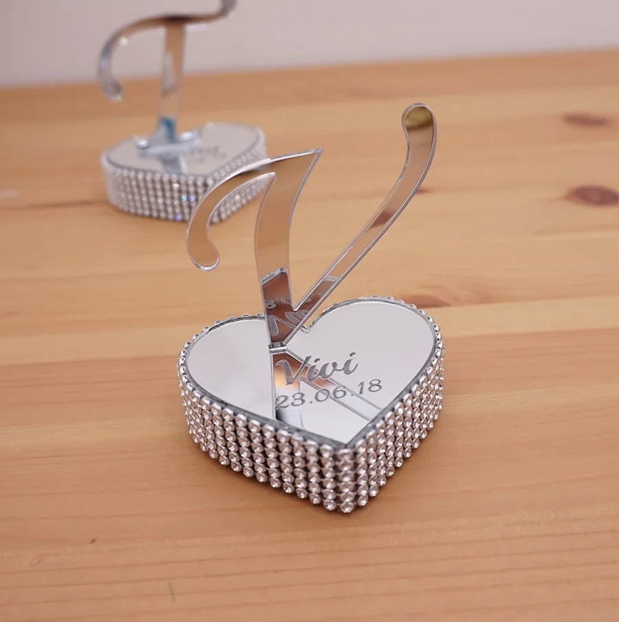 Heart-shaped mirror keychain with rhinestone edge, featuring a metal number 7 and engraved with the text "Vivi 28.06.18" on a wooden surface.