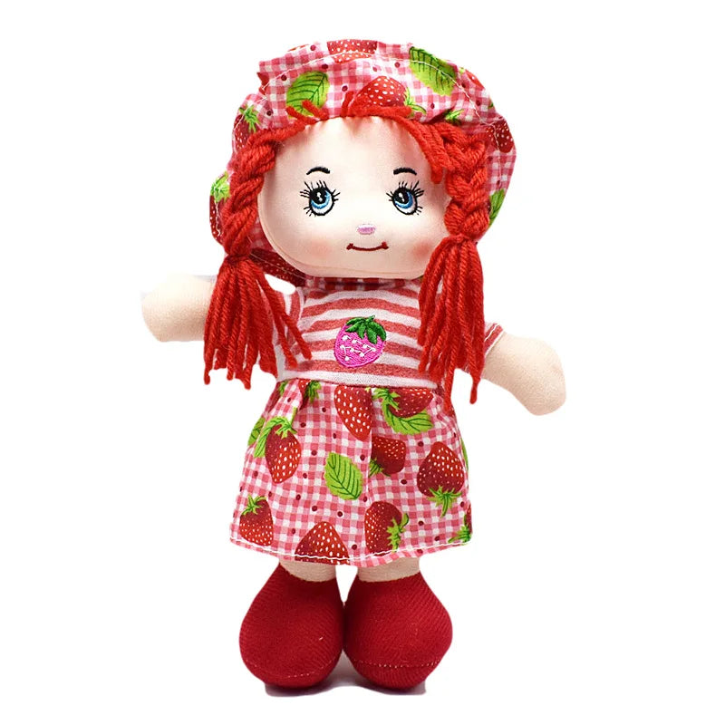 Rag doll with red yarn hair, wearing a strawberry-patterned dress and hat, red shoes, and a striped top with a strawberry emblem. The background is plain white.