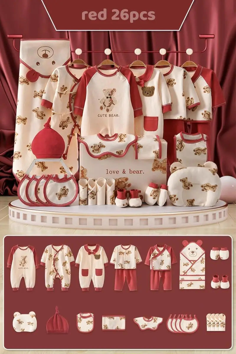 Red and cream baby clothing set with bear designs, includes onesies, tops, pants, bibs, hats, booties, and a blanket. Displayed on a tiered platform, labeled "red 26pcs."