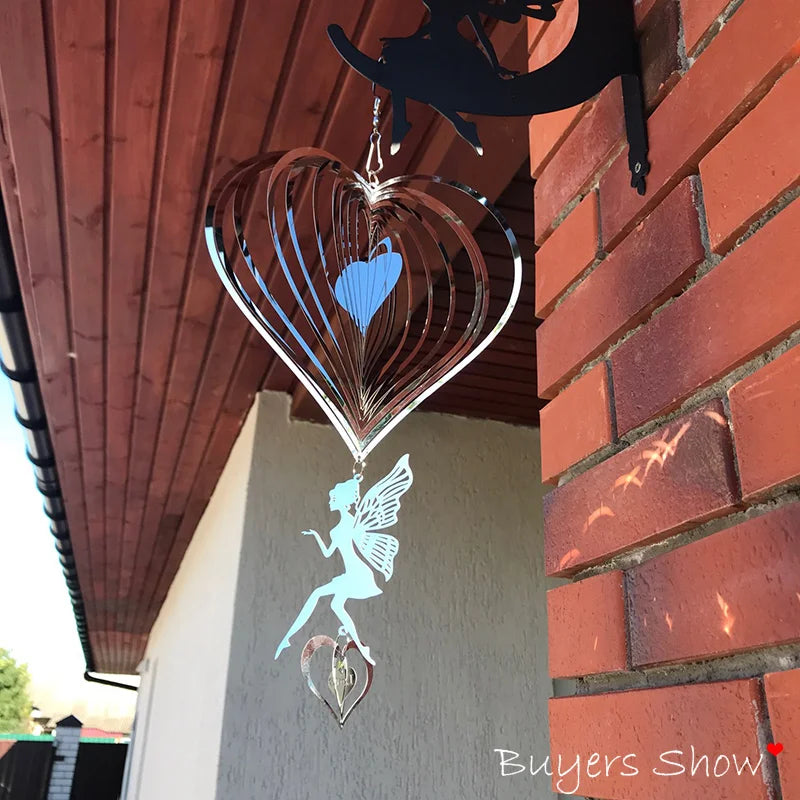 Hanging metal wind spinner shaped like a heart with a fairy and heart charm below, attached to a brick wall under a wooden roof.