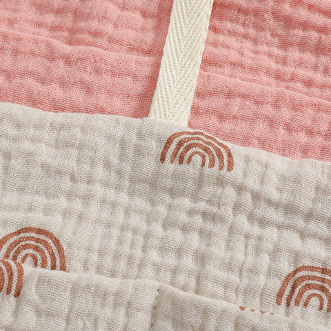 Close-up of textured fabric with a pink section and a cream section. The cream fabric features small, brown, semicircular rainbow patterns. A beige strip divides the sections.