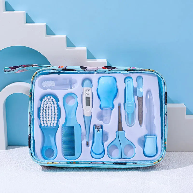 Baby grooming kit in a blue case on a white and blue background, containing a brush, comb, thermometer, nasal aspirator, scissors, nail clippers, and other hygiene tools.