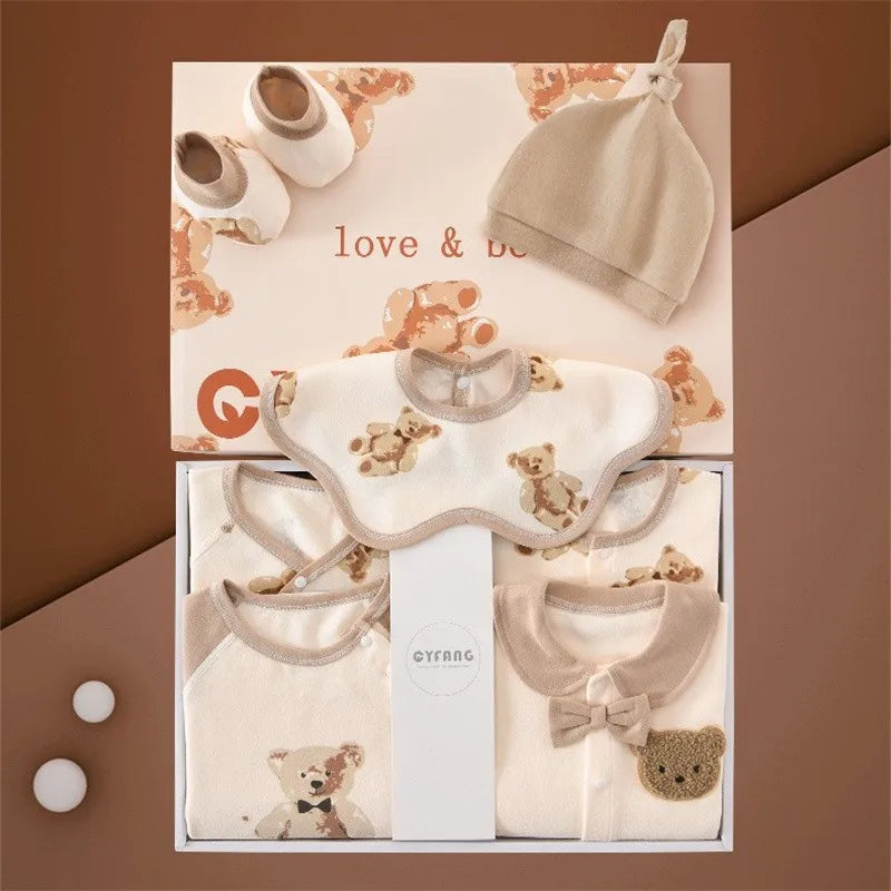 Baby clothing gift set with teddy bear designs includes a hat, bib, onesies, and soft shoes, displayed in a box with teddy bear print and "love & be" written on it.
