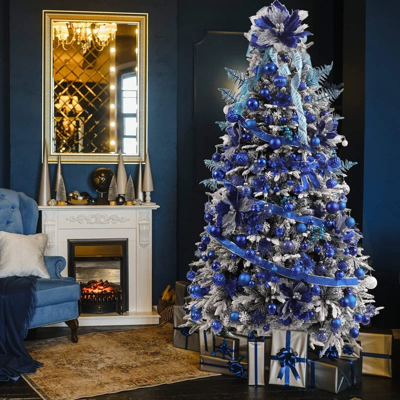 A festive living room with a Christmas tree decorated in blue and silver ornaments, next to a white fireplace with a mirror above. Gifts wrapped in silver and blue sit under the tree.