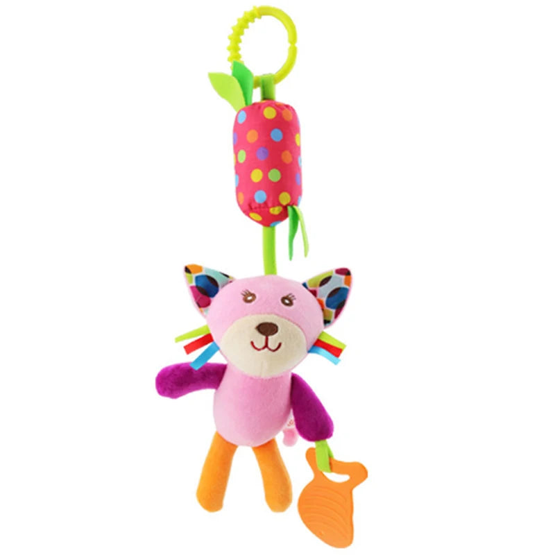 Colorful plush toy cat with polka-dot ears, holding an orange teether. It hangs from a green ring and a red, polka-dotted padding cylinder. Features multicolored ribbon whiskers.