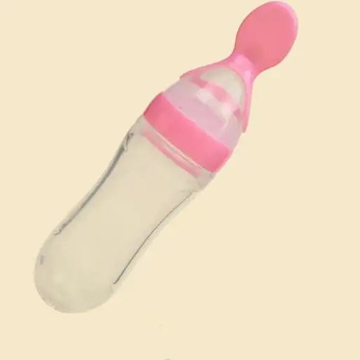 Clear baby bottle with pink accents and an attached soft spoon on a light background, designed for easy feeding and transitioning from bottle to spoon.