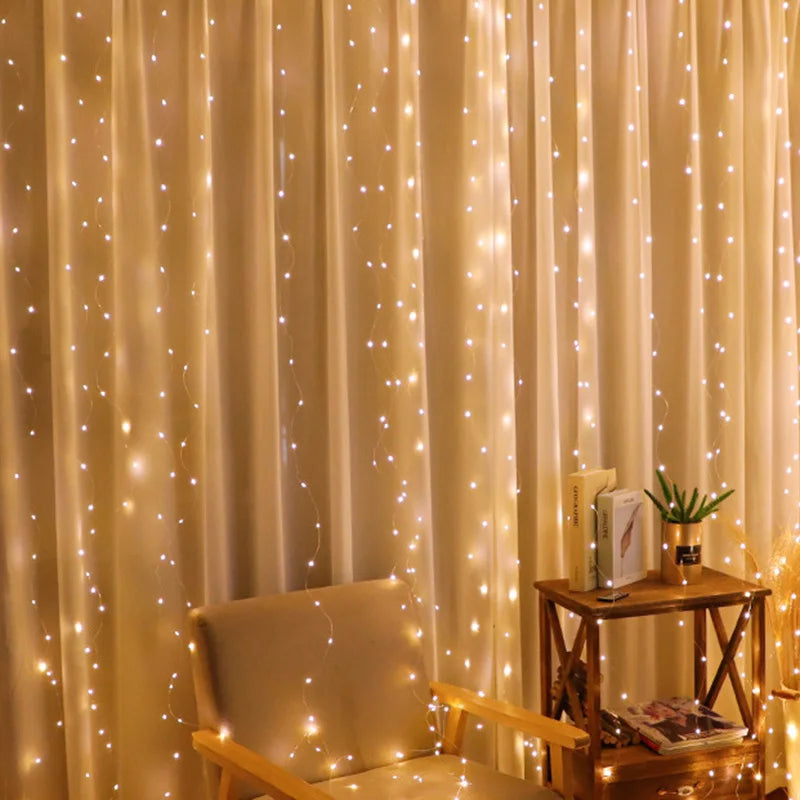 Cozy room with warm string lights draped over beige curtains. A soft armchair and a wooden side table with books and a small plant create an inviting atmosphere.