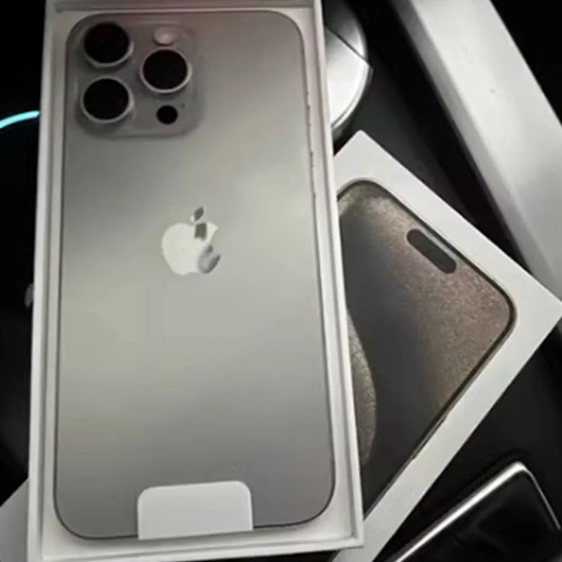 Silver iPhone with triple camera setup in open box, showing the Apple logo on the back. The phone rests on a black surface with the box lid partially visible.