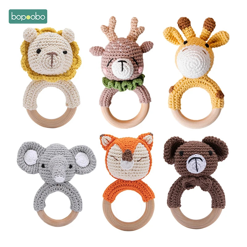 Six crocheted animal baby rattles with wooden rings. Includes a lion, deer, giraffe, elephant, fox, and bear, each with vibrant colors and unique designs.