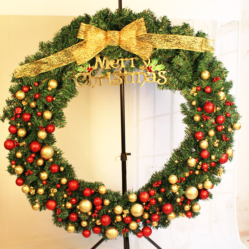 Christmas wreath adorned with red and gold ornaments and a large gold bow sits on a stand. "Merry Christmas" is displayed at the top, adding festive cheer.