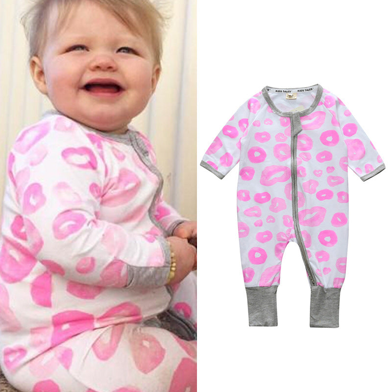 A baby wearing a white onesie with pink lip prints sits smiling. Next to the baby, the same onesie is displayed on a plain background, showing gray cuffs and trim with a front zipper.