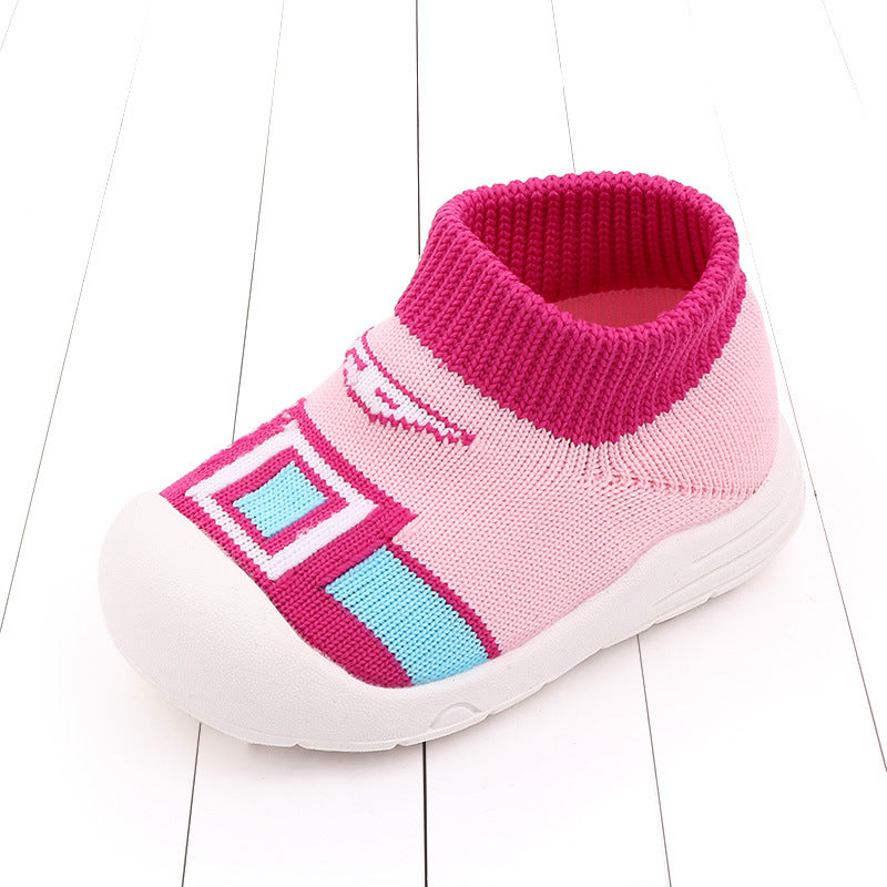 Pink and white children's shoe with a stretchy, sock-like upper. Features pink geometric patterns and a blue accent on the toe, with a white sole and textured grip.