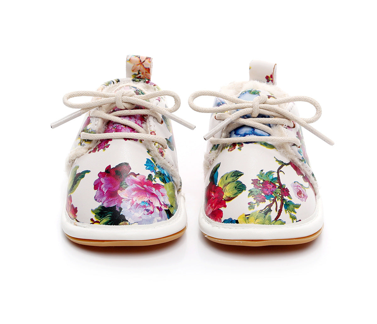 White toddler shoes with colorful floral patterns and beige laces, viewed from the front. The shoes have a bright, floral design with a soft lining and a loop pull on the back.