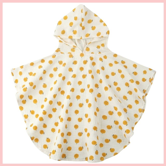 White hooded poncho for children with an all-over pattern of cheerful yellow smiley faces.